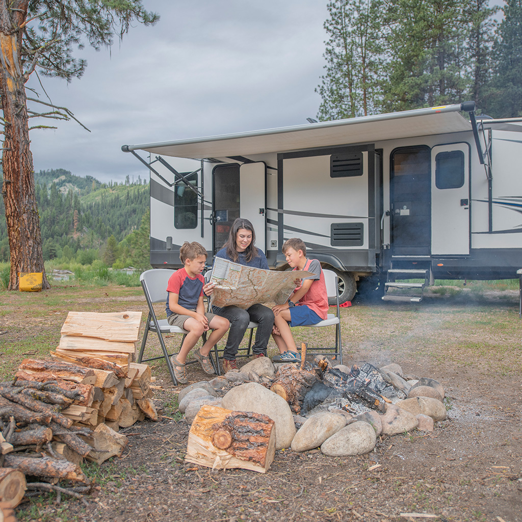 An outdoor meal beside a camper at a shaded campsite