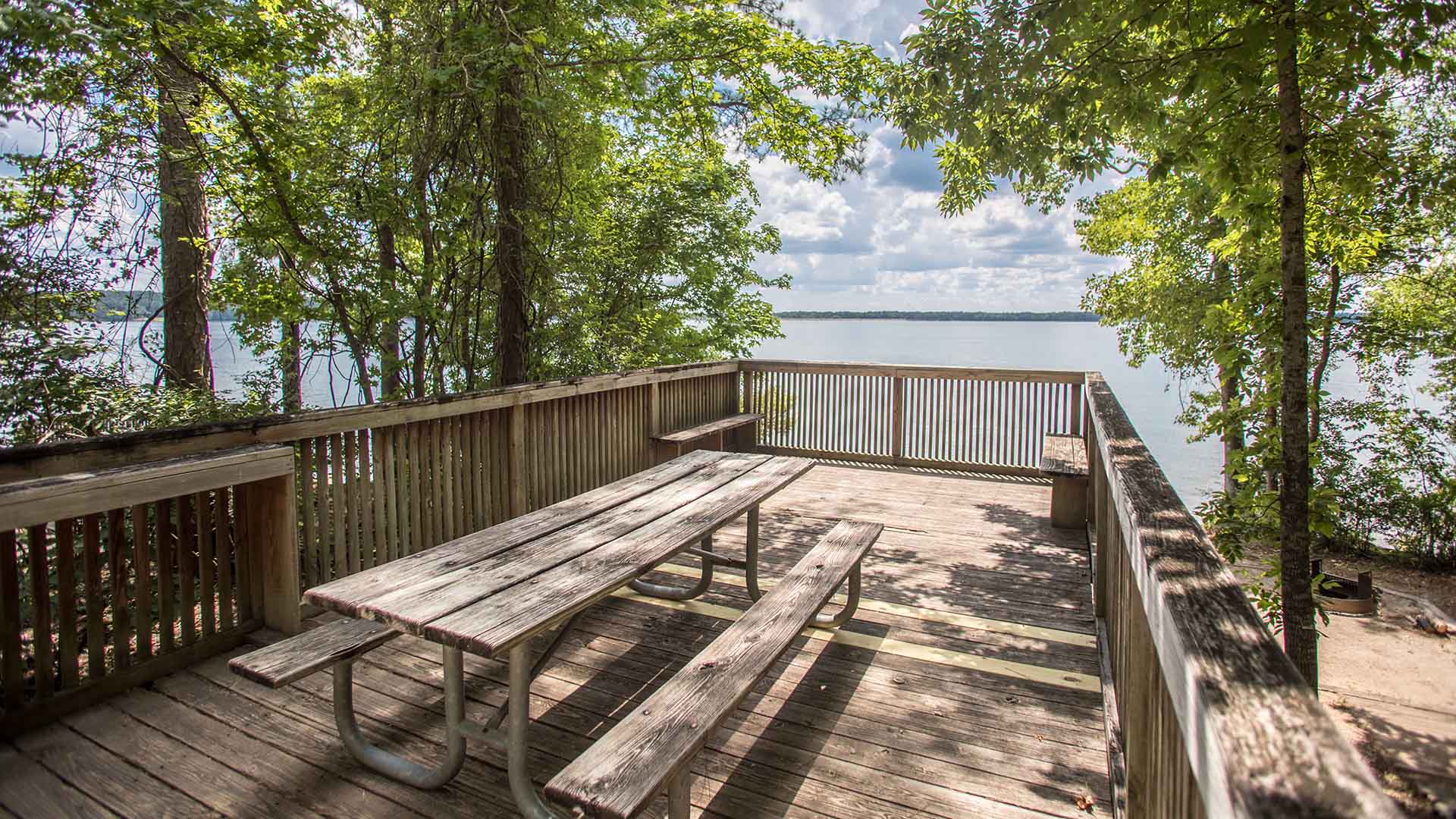 Picnic table on a shaded wooden deck overlooking West Point Lake at R. Shaefer Heard Park